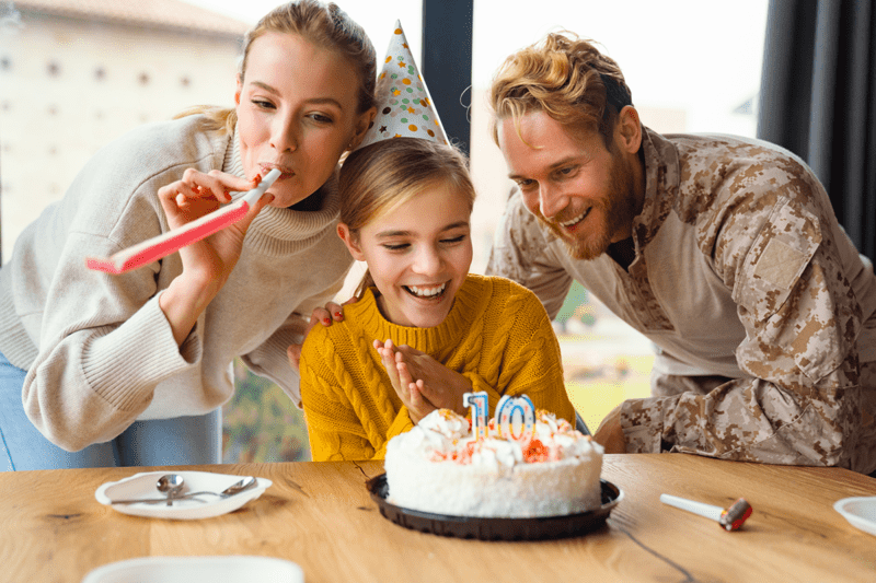 Family celebrating over a birthday cake with large windows in the background