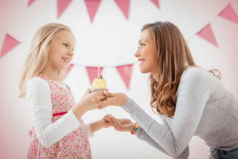 Mother giving her daughter a birthday cupcake
