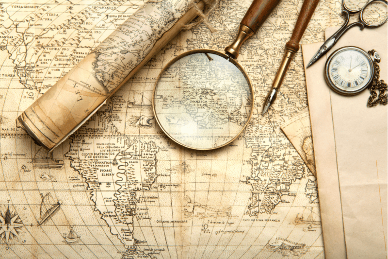 An old-style map with a magnifying glass, a compass, and a sextant.